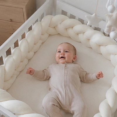 Tour de lit tresse beige avec bébé dans le berceau