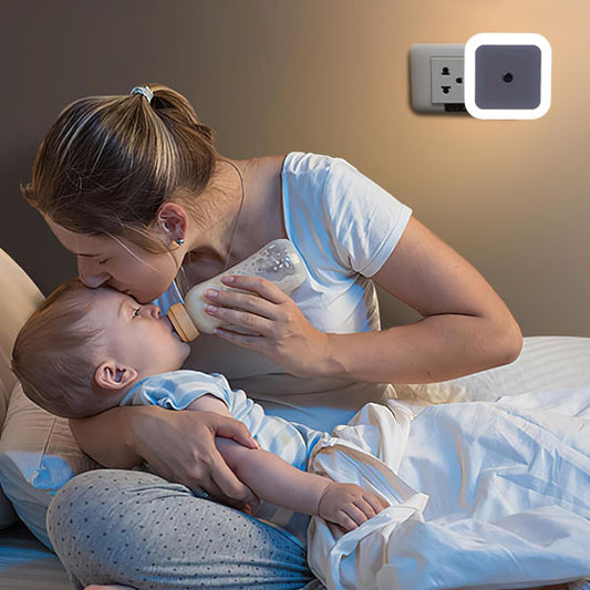 Une maman qui donne un biberon a on bébé en s'aidant de la veilleuse sur prise