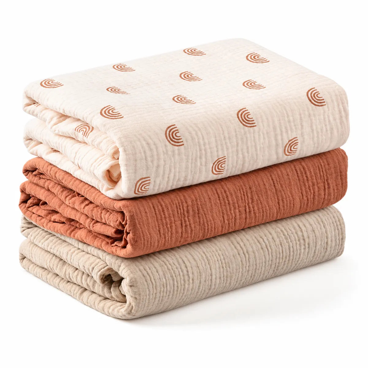 Lot de trois couvertures bébé pliées : écru à motifs arc-en-ciel, terracotta uni et beige uni.