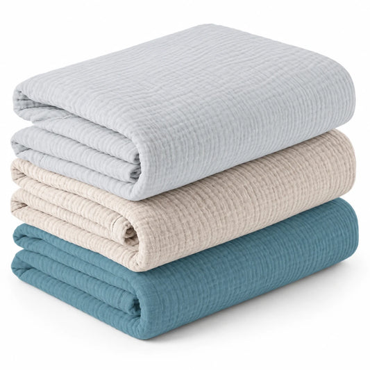 Lot de trois couvertures bébé unies pliées, gris perle, beige et bleu.