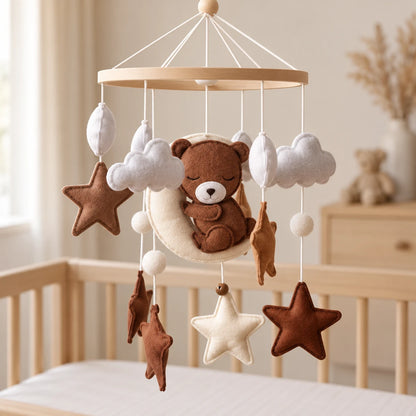 Détail de l’ours brun endormi sur son croissant de lune écru, avec nuages gris et étoiles brunes et claires.