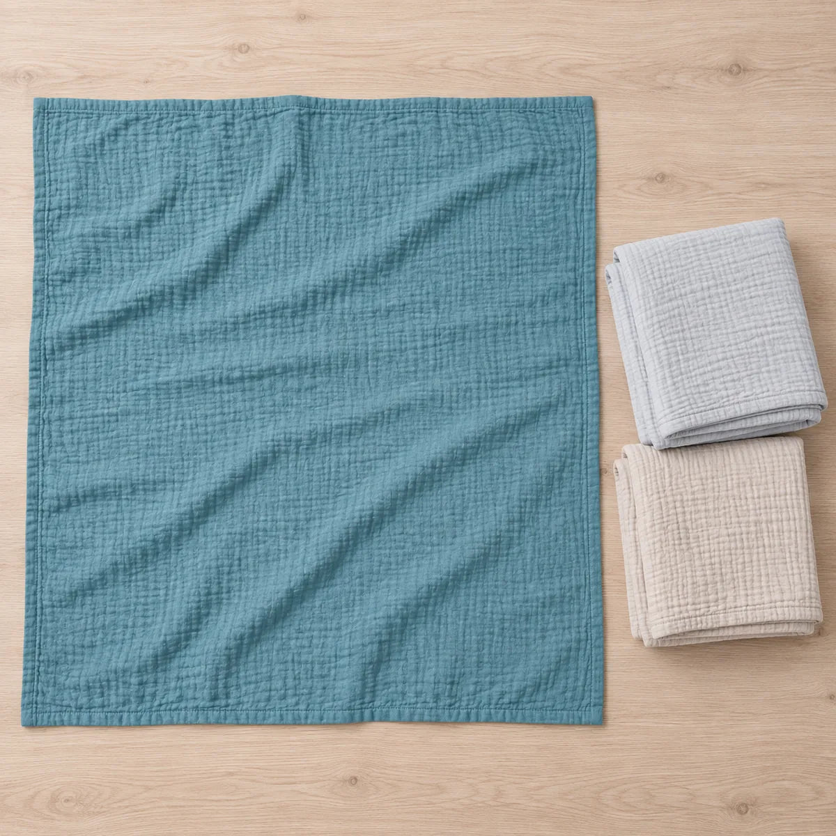 Couverture bleue dépliée à côté des couvertures beige et gris perle pliées du Trio Rivage.