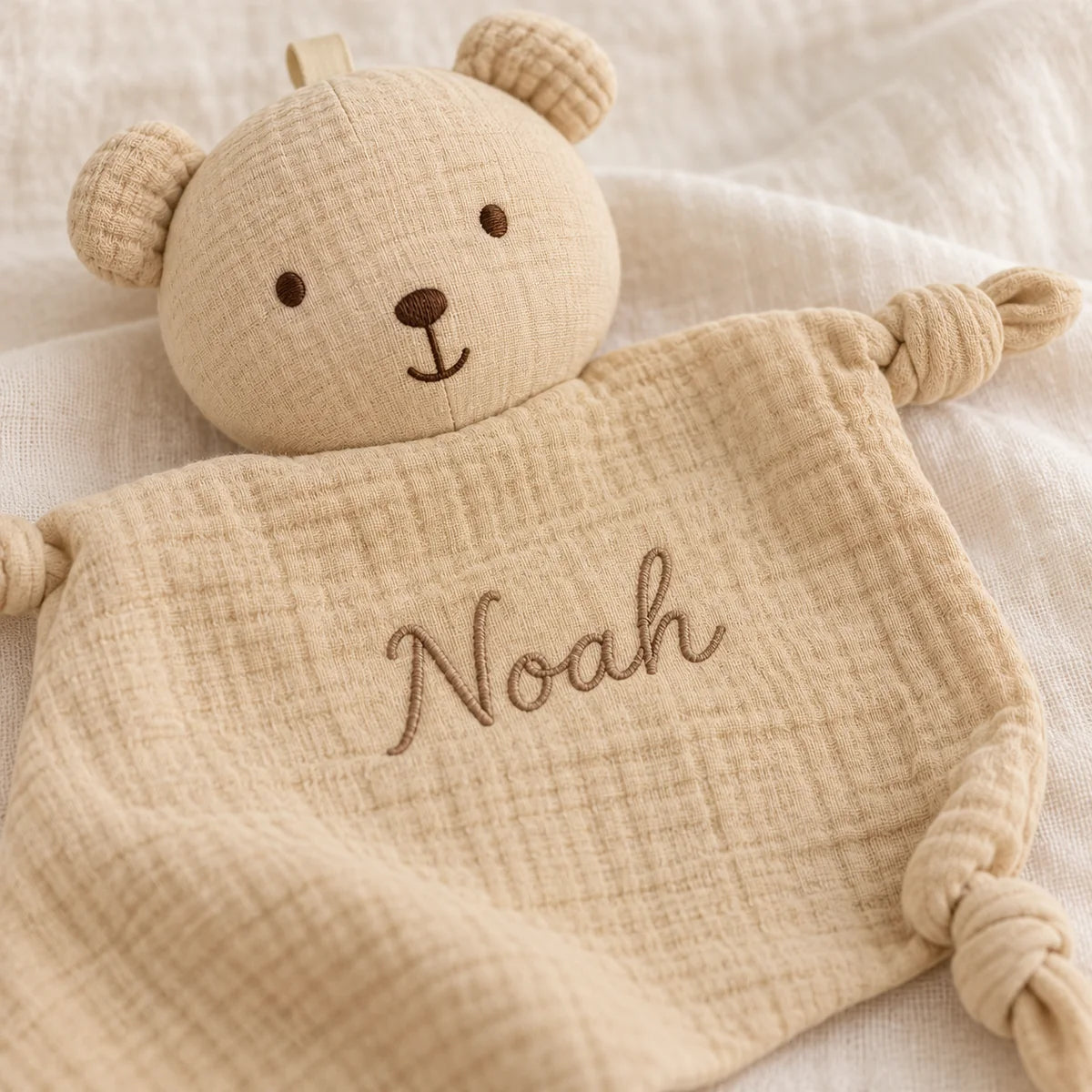 Détail du prénom Noah brodé sur le tissu beige du doudou ours