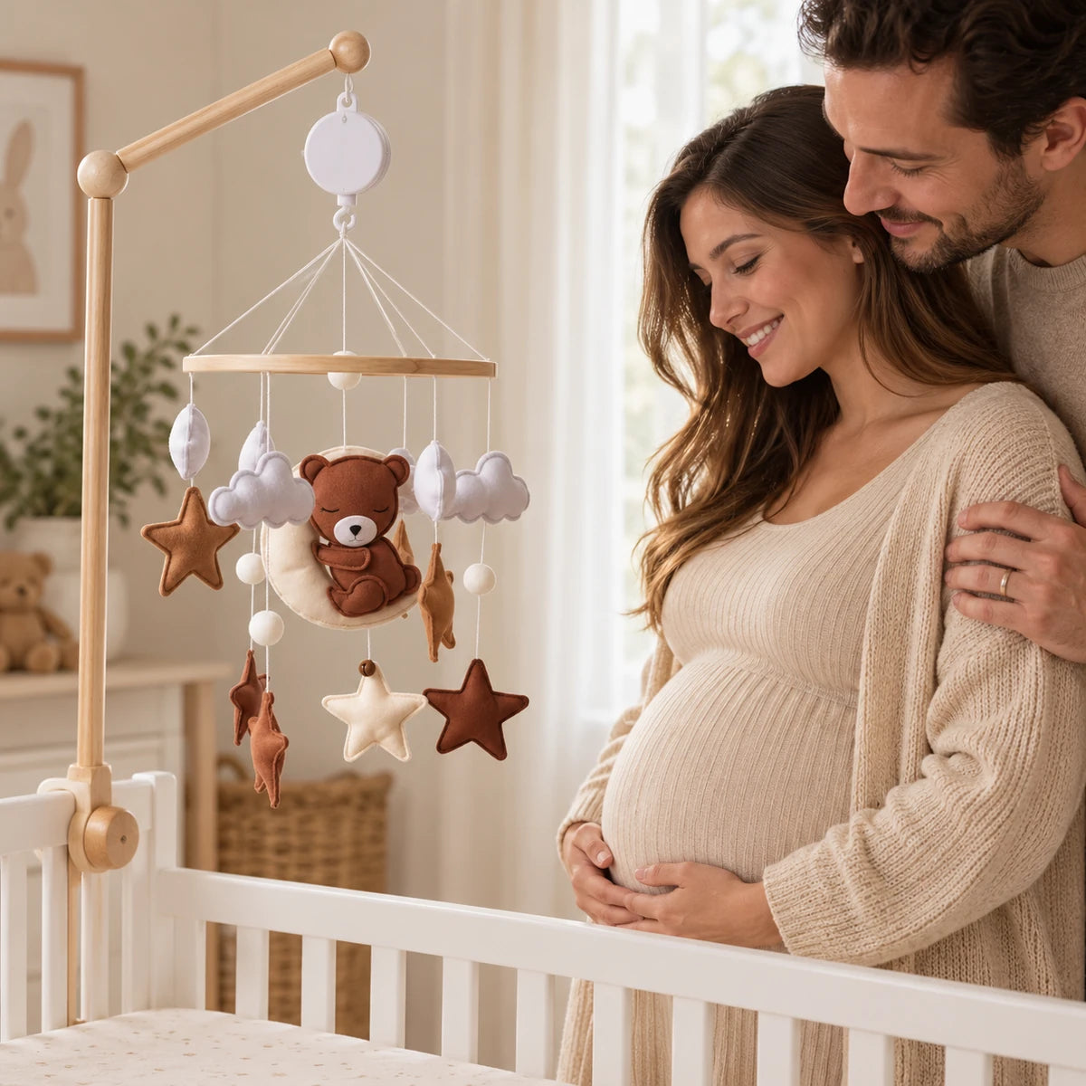 Futurs parents admirant le mobile Escale sur la Lune près d’un lit vide dans une chambre aux tons naturels.