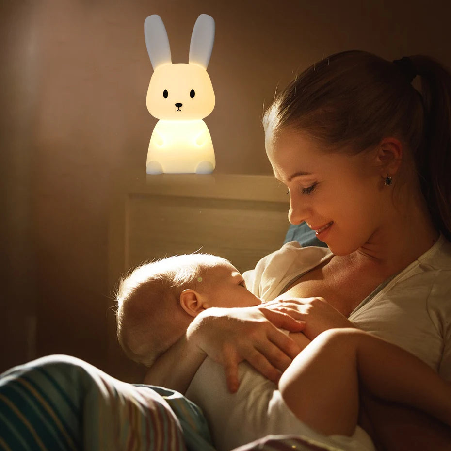 maman qui prend soins de son bébé sous la lumière de la veilleuse lapin