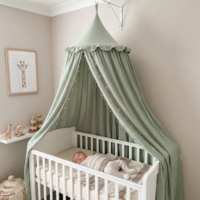 Bébé dort confortablement dans son lit protègé avec le Ciel de lit vert 