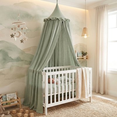 Bébé dort dans son lit décoré du Ciel de lit couleur vert