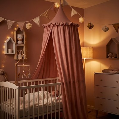 bébé dort paisiblement dans son lit protégé par le Ciel de lit rose
