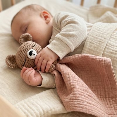 Bébé qui dort qui tient dans ses mains le Doudou bebe couleur kaki