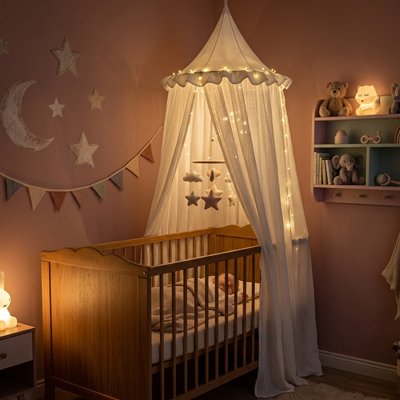 Ciel de lit blanc illuminé par une guirlande le soir dans la chambre bébé 
