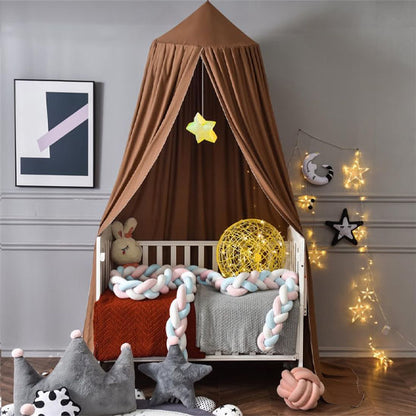 ciel de lit de couleur marron au-dessus d'un li bébé blanc et couverture rouge