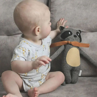 doudou raton laveur sur un sofa avec bébé