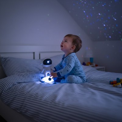Enfant dans son lit qui joue avec la Veilleuse projection astronaute
