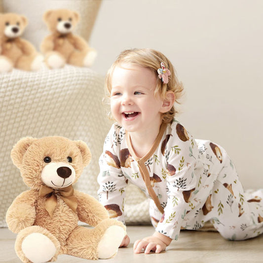ours en peluche de couleur beige avec petite fille blonde en pyjamas trés souriante