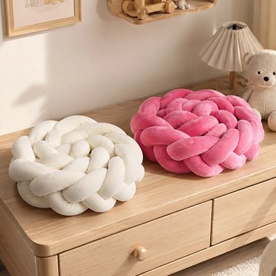 Tour de lit tresse beige et rose posés sur la table