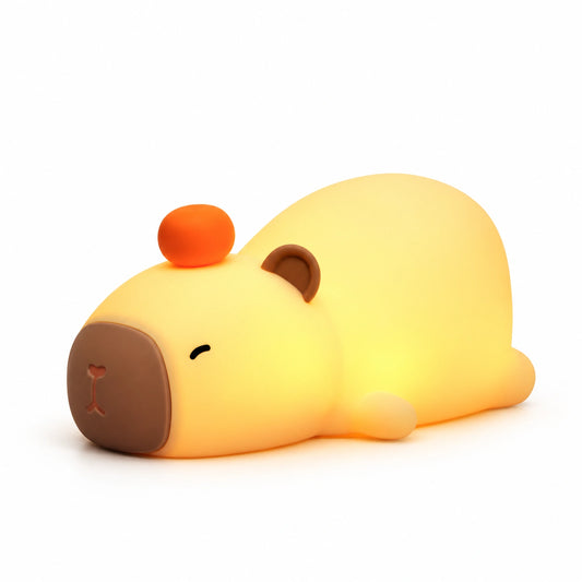 Veilleuse Capybara allumée avec une orange sur la tête, vue de trois quarts sur fond blanc