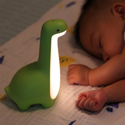 la veilleuse dinosaure de couleur verte éclaire un petit bébé qui dort