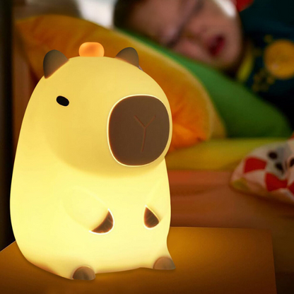 la veilleuse capybara allumé sur une table de chevet d'une chambre d'enfant