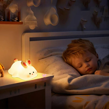 un garçon qui dort paisiblement dans son lit à côté de lui la veilleuse lapin Tommy