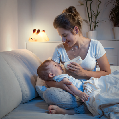 une maman qui donne un biberon à son bébé sous la lumière douce de la veilleuse Tommy