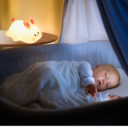 Tommy la veilleuse lapin est à côté du bébé qui dort dans son berceau
