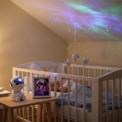 bébé dort paisiblement dans la chambre avec la lumière céleste de la veilleuse projection astronaute