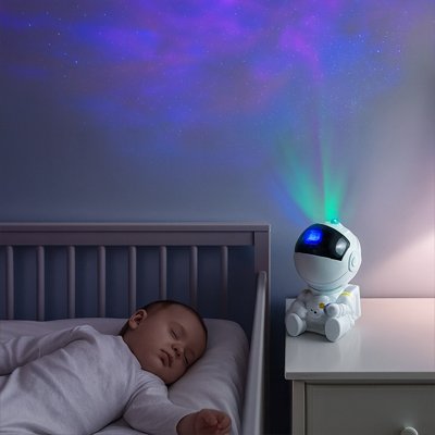 la veilleuse projection est sur la table de nuit et illumine d'un effet boreal la chambre bébé